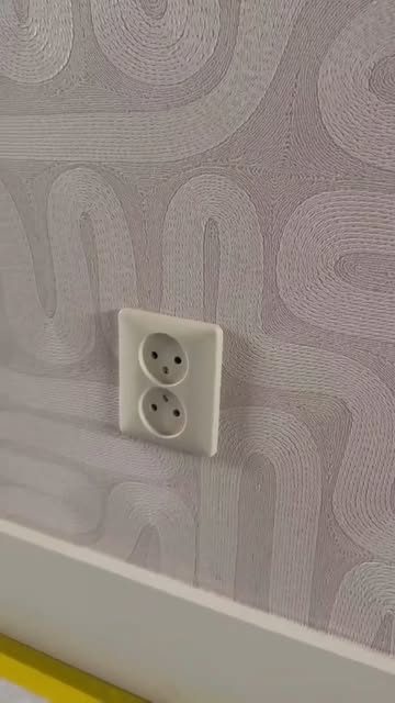 Close-up of a textured grey wallpaper fitted around a socket
