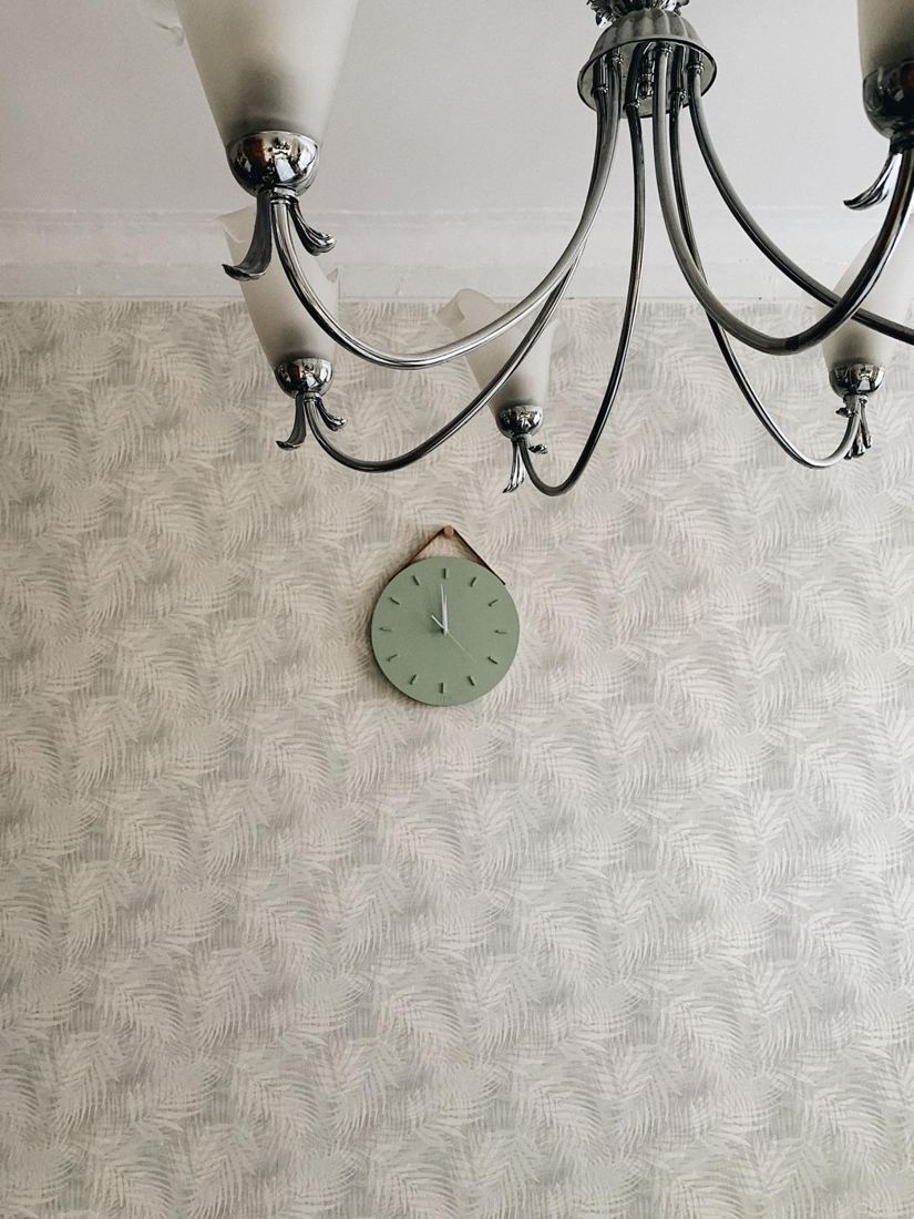 Textured wallpaper with a mint wall clock under a chandelier